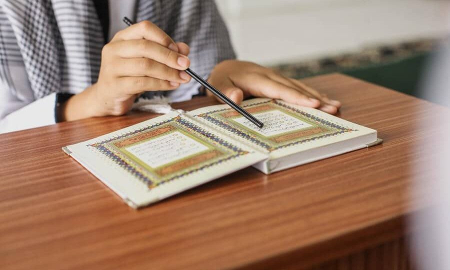 close-up-portrait-muslim-man-hands-pointing-letters-while-reading-quran-with-stick_368093-4032
